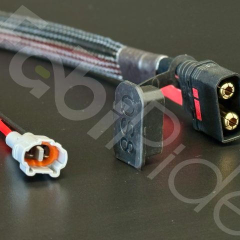 Iš arti nufotografuoti automobilių laidai su 2 kontaktų jungtimi ir apsaugotu SAE maitinimo kištuku su dangteliu.